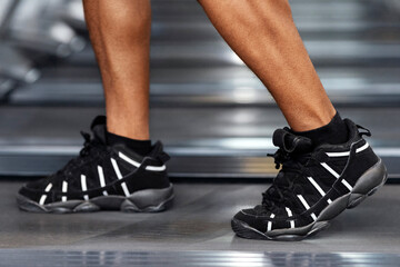 Sports shoes for gym concept. Closeup of unrecognizable african american man bodybuilder legs...