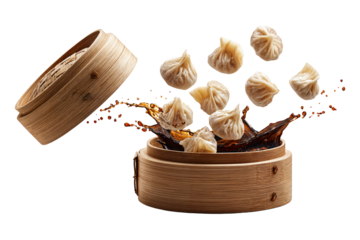 Steamed soup dumplings xiao long bao flying with soy sauce splash in bamboo steamer isolated on transparent background
