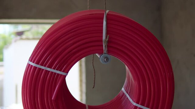 Red plastic pipe coil hanging on construction site