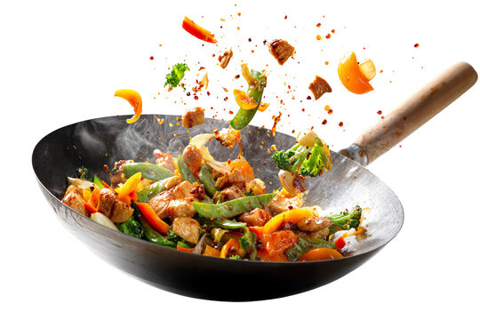 Colorful chicken stir fry with vegetables in hot wok isolated on transparent background with flying ingredients and spices