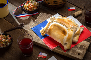 Traditional Chilean empanadas served on a rustic table with sauce and wine, national holidays, September 18th