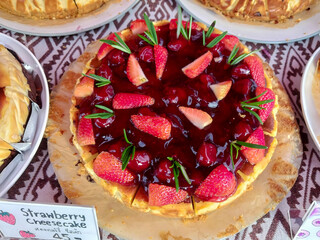 Strawberry cheesecake with fresh strawberries on top, sold at the market.