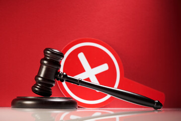 wooden gavel and cross mark on red background.