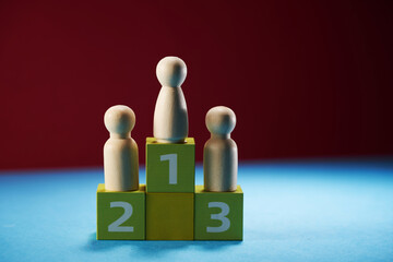 wooden figures of female likeness stand on a pedestal of their cubes on a red background.