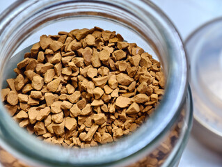Close-up of instant coffee granules in a glass jar – aromatic, textured, and rich brown tones....