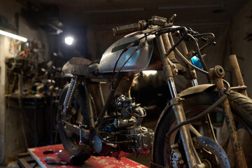 No people shot of custom motorcycle in workshop with tools on metal parts in garage setting