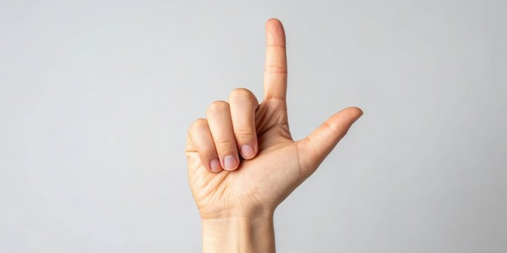 Hand making a 'L' gesture against a neutral background.