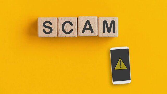 For investment scam, fraud and Ponzi scheme concept. animated video of  SCAM text on wooden cube blocks  and exclamation mark on mobile phone with yellow background