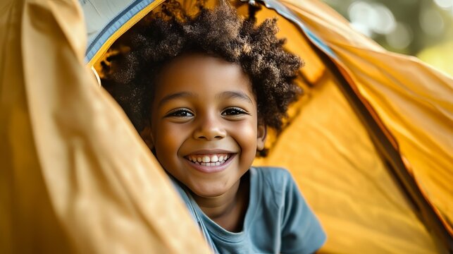 Happy African American child spending time during vacation in a camping tent in a national park