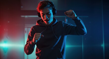 Energetic young person dancing while wearing headphones illuminated by red and blue lighting in a modern interior setting showcasing joyful movement and lifestyle with copy space for digital content