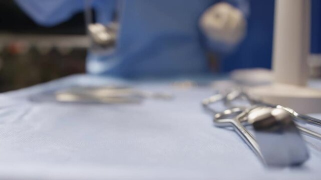 A surgeon prepares sterile surgical instruments on an operating table