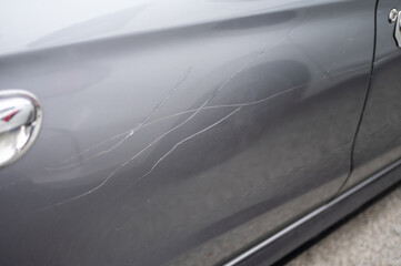 Grey car door with multiple long scratches