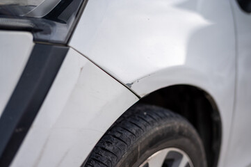 Chipped paint and slight dent on car fender above tire