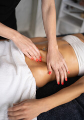 Therapist massaging woman's abdomen in wellness center