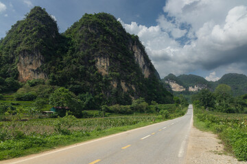 Long straight road stretching through the scenic rural landscape of Cao Bang province in northern Vietnam with huge limestone karst mountains towering on all sides