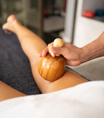 Maderotherapy massage, masseur using wooden tool massaging woman leg in spa or beauty center
