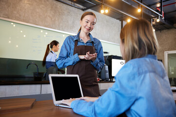 young barista meeting and talking with customer in the cafe