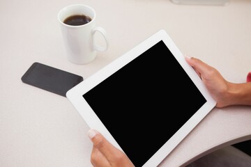 Flat design red sleeve hands are holding white framed tablet over desk with mug and smartphone