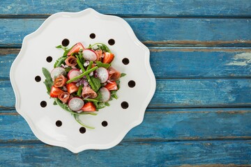 Fresh salad in white plate on blue table