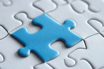 Fototapeta premium Close-up of vibrant blue puzzle piece above a white puzzle with one piece missing