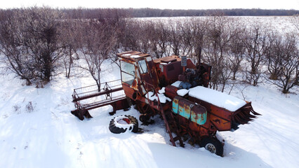 Old broken harvester abandoned in snowed countryside
