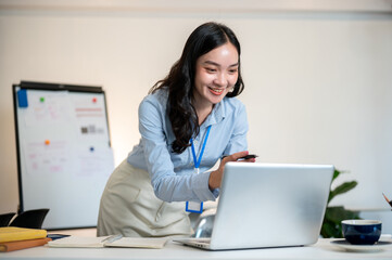 Female office worker or businesswoman looking excited as leaning over a table to look at her laptop.