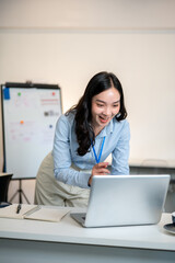 Female office worker or businesswoman looking excited as leaning over a table to look at her laptop.