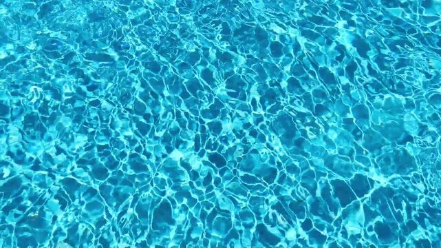 Clear blue pool water with shimmering light reflections on the surface. Perfect for backdrops, tourism advertising or poolside lifestyle concepts.