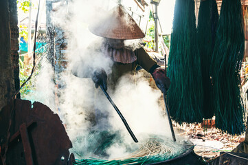Vietnamese woman dyes reeds at woven sleeping mat factory in Vietnam