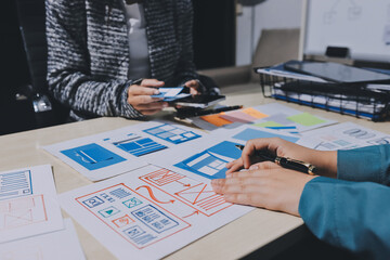 Group of young application developers analyzing uxui mobile app templates during a working meeting