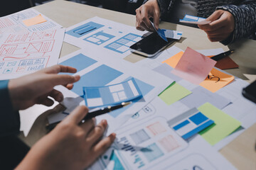 Group of young application developers analyzing uxui mobile app templates during a working meeting