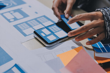 Group of young application developers analyzing uxui mobile app templates during a working meeting