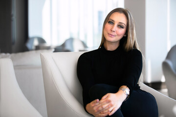 Confident Woman Relaxing in a Modern Lounge Space During Daylight With Stylish Interior Design Elements