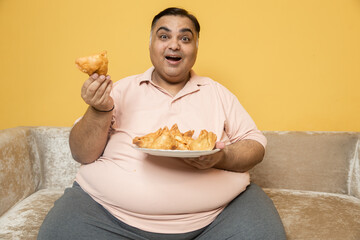 Hungary overweight indian man enjoy unhealthy samosa snack. Plus size Fat guy eating fried junk food. Obesity and weight gain.