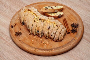 Delicious sliced biscotti with cranberries, nuts, and spices on a wooden board setting.