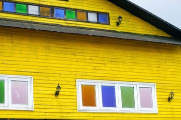 Vibrant Yellow Wooden House with Colorful Windows and Lanterns