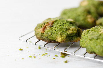 Closeup of fresh baked matcha cookies on white wooden background.