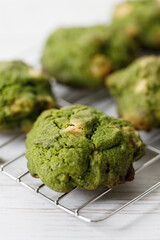 Closeup of fresh baked matcha cookies on white wooden background.