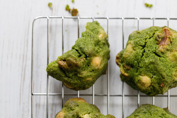Closeup of fresh baked matcha cookies on white wooden background.