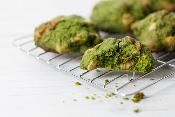 Closeup of fresh baked matcha cookies on white wooden background.