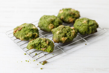Closeup of fresh baked matcha cookies on white wooden background.
