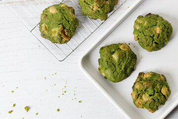 Closeup of fresh baked matcha cookies on white wooden background.