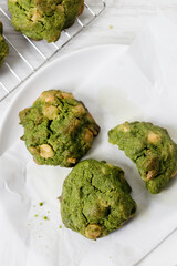 Closeup of fresh baked matcha cookies on white wooden background.