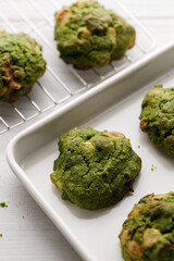 Closeup of fresh baked matcha cookies on white wooden background.
