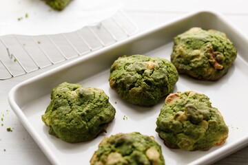 Closeup of fresh baked matcha cookies on white wooden background.