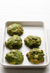 Closeup of fresh baked matcha cookies on white wooden background.