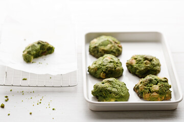 Closeup of fresh baked matcha cookies on white wooden background.