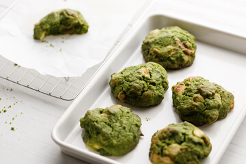 Closeup of fresh baked matcha cookies on white wooden background.