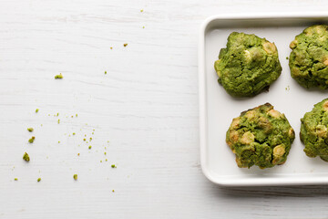 Closeup of fresh baked matcha cookies on white wooden background.