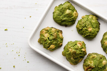 Closeup of fresh baked matcha cookies on white wooden background.